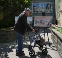 A resident of a long-term care home stops to look at renderings of the new Richmond Lions Manor-Fentiman care home before a provincial government news conference announcing the project, in Richmond, B.C., on Thursday, June 22, 2023. Darryl Dyck/The Canadian Press. 