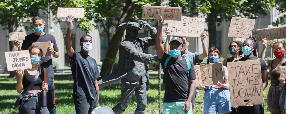 People take part in a protest next to the James McGill statue in Montreal, Saturday, August 1, 2020, where they called on the university to take down the statue. Graham Hughes/The Canadian Press. 