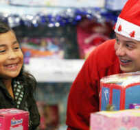 Emily Enriquez, 8, smiles as she gets to pick out her Christmas presents joined by volunteer Jessyka Spishaktaju at the Midnight Mission on Tuesday Dec. 25, 2012. Richard Vogel/AP Photo. 