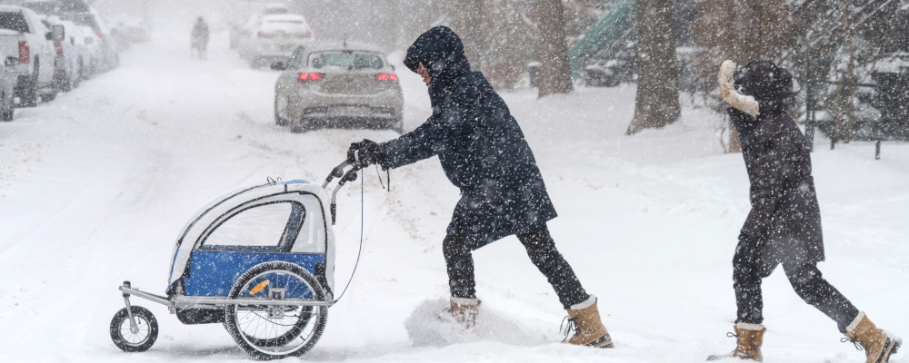 A man pushes a stroller during a winter snowstorm in Montreal on Monday, January 17, 2022. Paul Chiasson/The Canadian Press. 