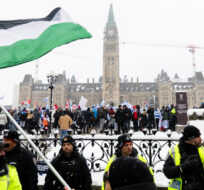 A pro-Palestinian protestor waves a Palestinian flag on Wellington St., as pro-Israel protestors rally on Parliament Hill in Ottawa, on Monday, Dec. 4, 2023. Spencer Colby/The Canadian Press. 