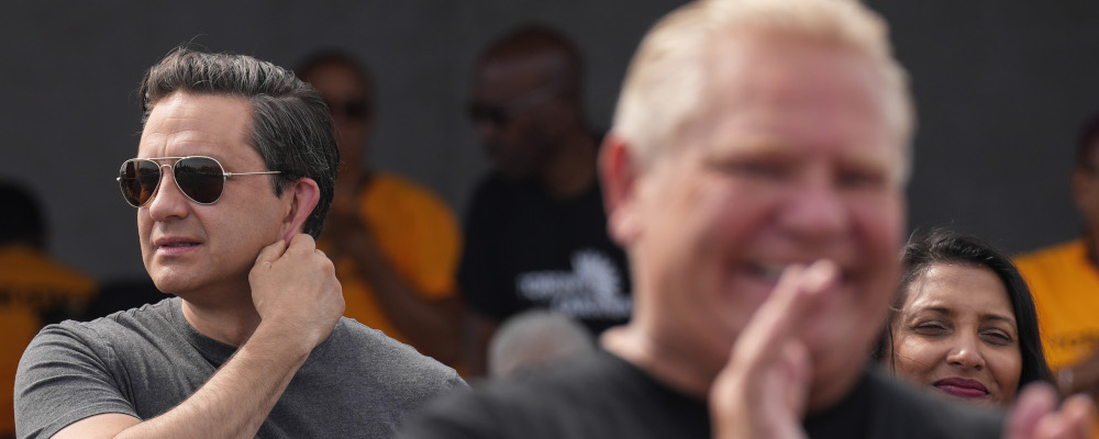 Federal Conservative Leader Pierre Poilievre (left) watches as Ontario Premier Doug Ford delivers remarks before the start of the Toronto Caribbean Carnival, on Saturday, August 5, 2023. Chris Young/The Canadian Press. 