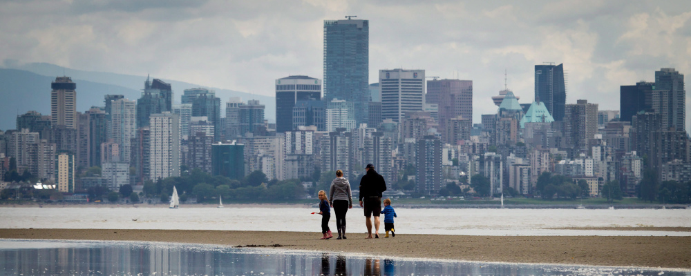 A family walks along a sandbar between tidal pools off Spanish Banks Beach as the tide comes in, in Vancouver B.C., on Monday May 20, 2013. Darryl Dyck/The Canadian Press. 