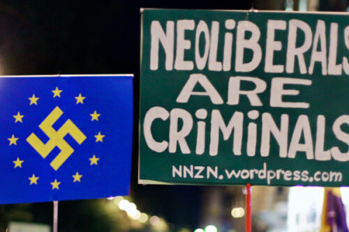 Protestors holds banners reading "neoliberals are criminals" and a EU flag with the nazi symbol on it during a demonstration outside Parliament as lawmakers debate budget spending cuts for 2013 in Madrid, Spain, Tuesday, Oct. 23, 2012. Andres Kudacki/AP Photo. 