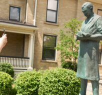 Allison Mimlos takes a photograph of a statue of Sir Frederick Banting at Banting House National Historic Site in London, Ont., Saturday, June 29, 2019. Geoff Robins/The Canadian Press. 