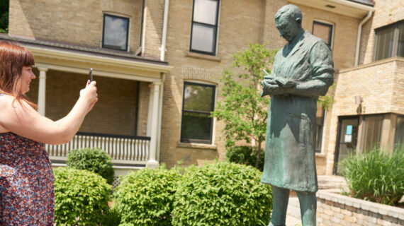 Allison Mimlos takes a photograph of a statue of Sir Frederick Banting at Banting House National Historic Site in London, Ont., Saturday, June 29, 2019. Geoff Robins/The Canadian Press. 