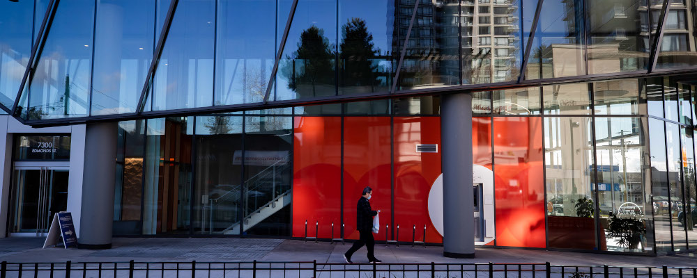 A man walks past a commercial and office space building attached to a condo tower, in Burnaby, B.C., on Sunday, February 7, 2021. Darryl Dyck/The Canadian Press. 