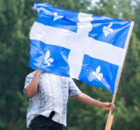 A man walks through a park with a Quebec flag on Saint-Jean-Baptiste Day in Montreal, Thursday, June 24, 2021. Graham Hughes/The Canadian Press. 