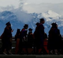 Spring 2020 graduates are silhouetted against the mountains as they line up for a convocation ceremony at Simon Fraser University, in Burnaby, B.C., on Friday, May 6, 2022. Darryl Dyck/The Canadian Press. 