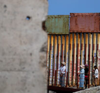 People walk along the wall that separates the United States from Mexico, near a slab of the Berlin Wall, in Tijuana, Mexico, Friday, Aug. 25, 2023. Gregory Bull/AP Photo.