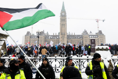 A pro-Palestinian protestor waves a Palestinian flag on Wellington St., as pro-Israel protestors rally on Parliament Hill in Ottawa. Spencer Colby/The Canadian Press.