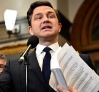 Conservative Leader Pierre Poilievre holds recently released documents about two scientists who were fired from the National Microbiology Lab in Winnipeg, in Ottawa, on Thursday, Feb. 29, 2024. Justin Tang/The Canadian Press.