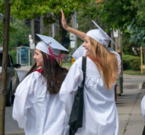 Notre Dame High School graduates (left to right) Lauryn Madigan, Meg Botelho and Claire Lackey wave to honking drivers as they celebrate with a walk down a street in Toronto on Monday, June 22, 2020. Frank Gunn/The Canadian Press.