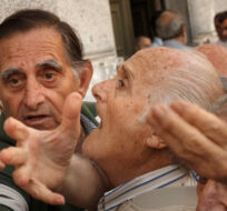 In this photo taken on Wednesday, July 1, 2015, pensioners try to get a number to enter inside a bank in Athens. Daniel Ochoa de Olza/AP Photo. 