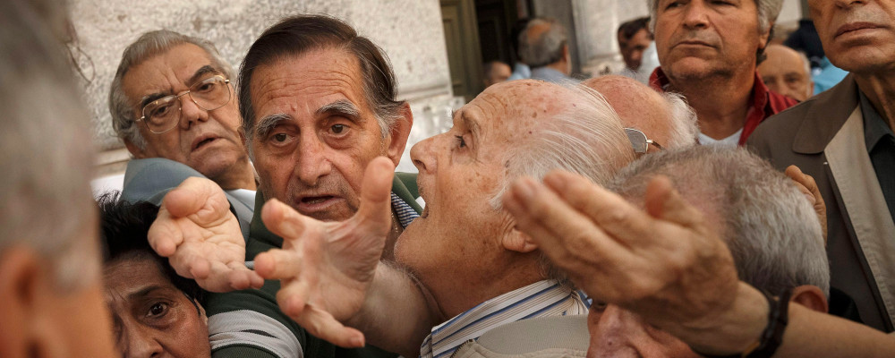 In this photo taken on Wednesday, July 1, 2015, pensioners try to get a number to enter inside a bank in Athens. Daniel Ochoa de Olza/AP Photo. 