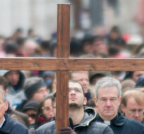 A man walks with a crucifix along with the faithful as they participate in the Way of the Cross on Good Friday in Montreal, April 18, 2014. Graham Hughes/The Canadian Press. 