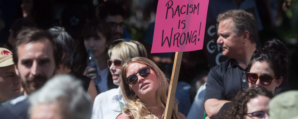 A woman holds a sign during an anti-racism rally held as a counter protest to an alt-right rally at City Hall in Vancouver, B.C., on Saturday August 19, 2017. Darryl Dyck/The Canadian Press. 