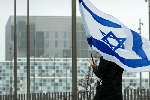 A woman holds an Israeli flag in front of International Criminal Court at The Hague, Netherlands. Martin Meissner/AP Photo. 