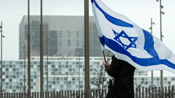 A woman holds an Israeli flag in front of International Criminal Court at The Hague, Netherlands. Martin Meissner/AP Photo. 