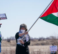 A person waves a Palestinian flag outside of Wanuskewin Heritage Park near Saskatoon, Sask., on Tuesday, April 23, 2024. Heywood Yu/The Canadian Press. 