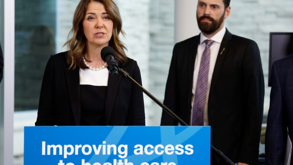 A line of people waiting outside a Canadian hospital entrance.